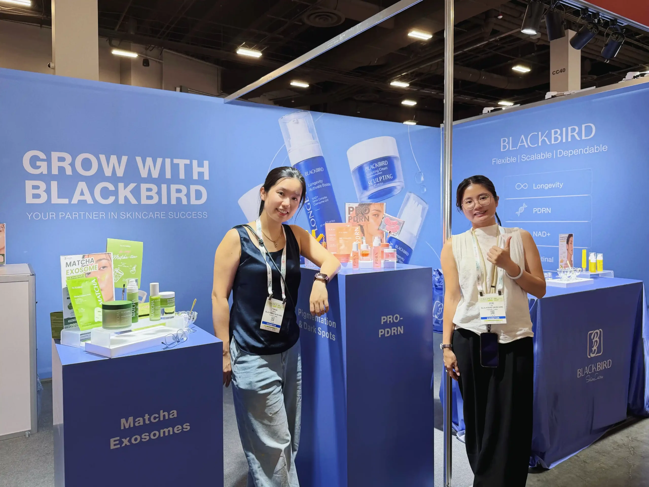 Two Blackbird team members alongside skincare product displays at the exhibition booth.